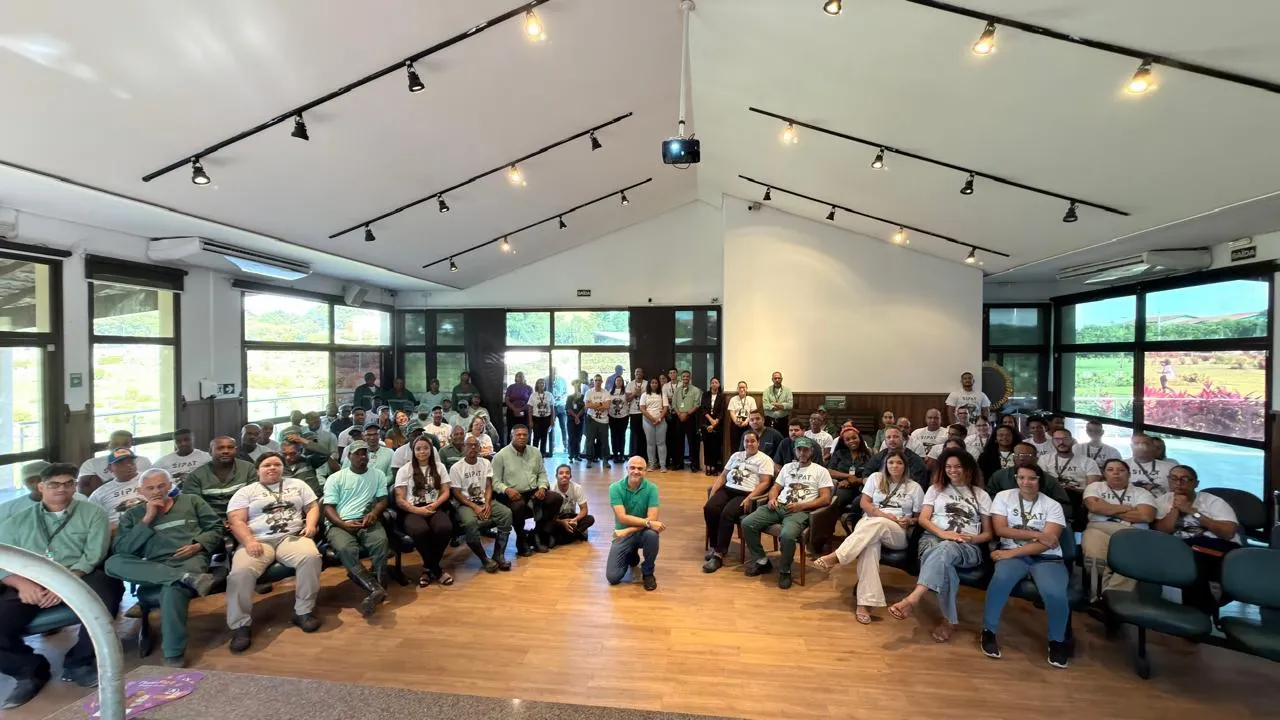 Colaboradores reunidos em auditório com vista para a mata